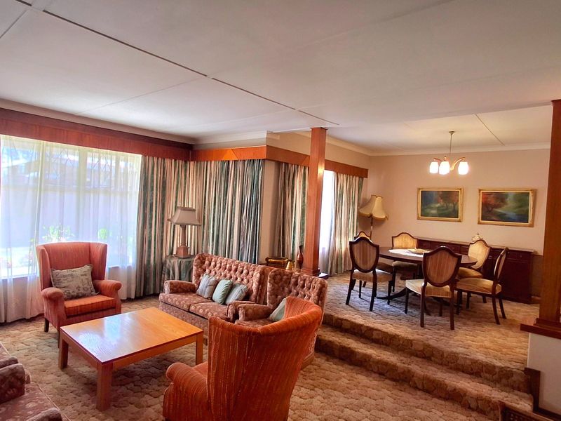 Spacious open-plan living and dining area featuring a sunken lounge, raised dining platform, and traditional timber architectural detailing.