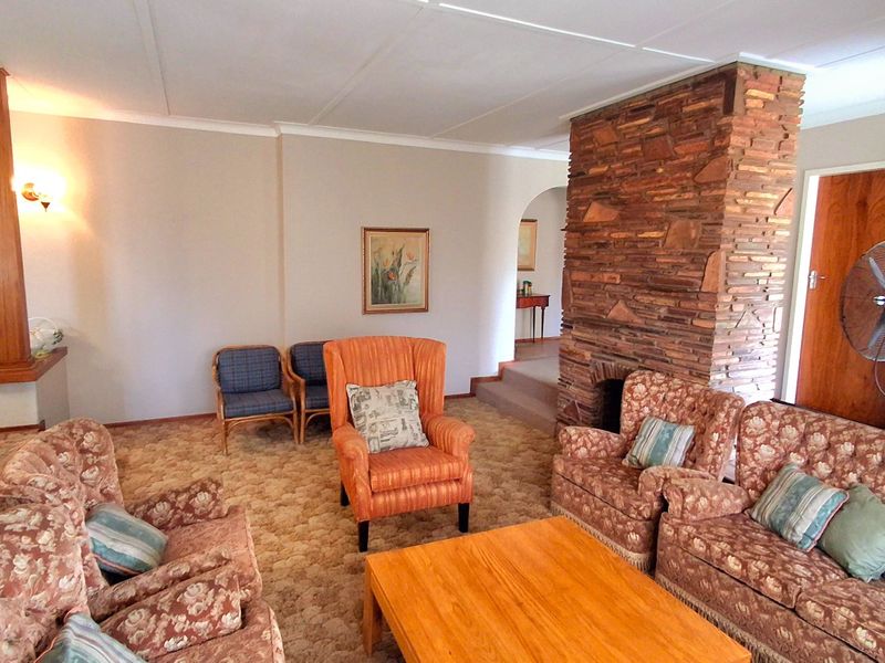 Spacious living room featuring a prominent stone fireplace, timber architectural detailing, and an arched transition to adjacent living areas.