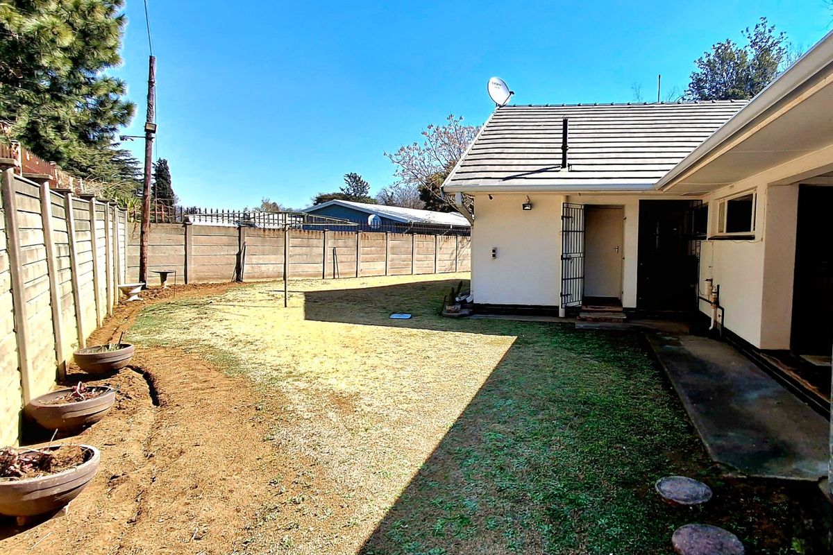 Rear exterior view of the property featuring a private garden, concrete boundary wall, and access to the rear entrance.