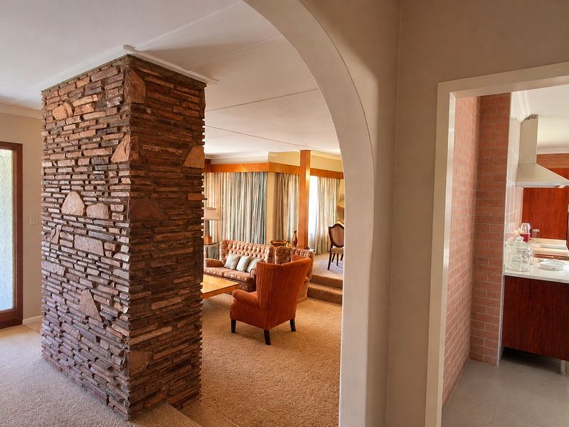 Open plan living area featuring a prominent stone feature pillar, arched transition, and a modern kitchen with built-in cabinetry and stainless steel appliances.