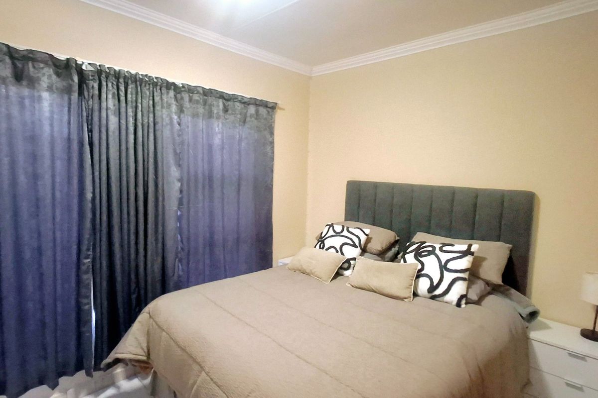 A standard bedroom featuring neutral wall tones and decorative ceiling cornicing, providing a comfortable and functional sleeping space.
