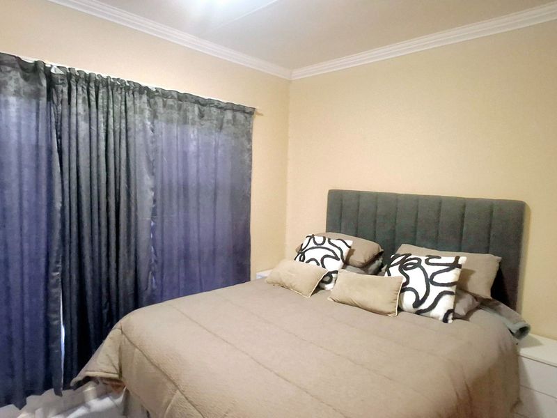 A standard bedroom featuring neutral wall tones and decorative ceiling cornicing, providing a comfortable and functional sleeping space.