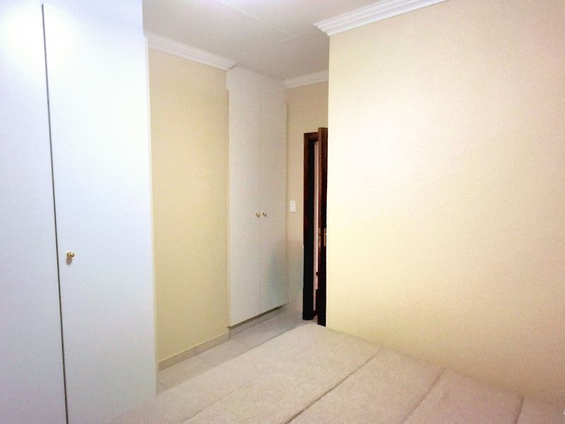 A bedroom featuring built-in cupboards, tiled flooring, and decorative cornice detailing.