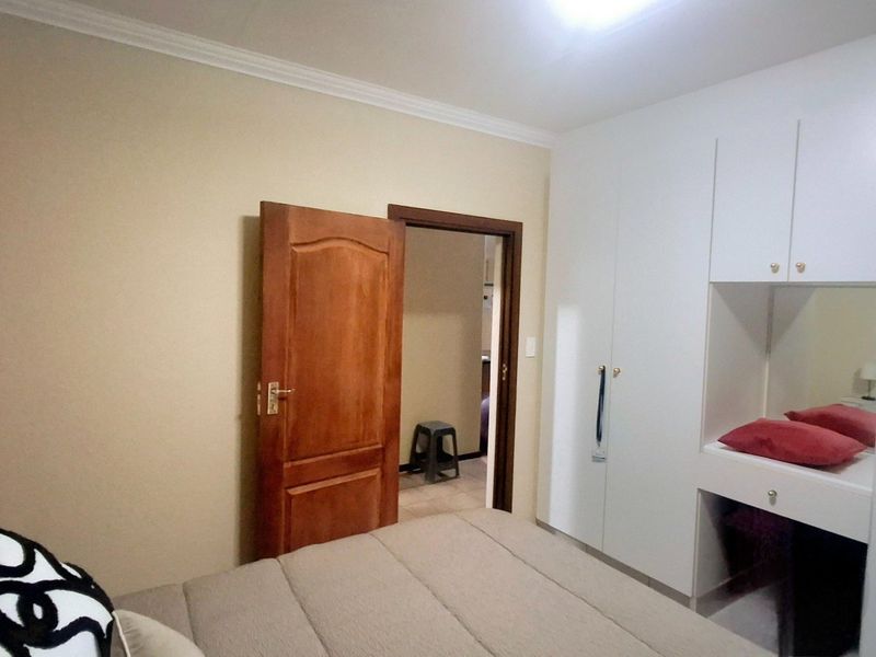 Bedroom featuring a built-in wardrobe with integrated vanity unit, neutral wall finishes, and classic coving detail.