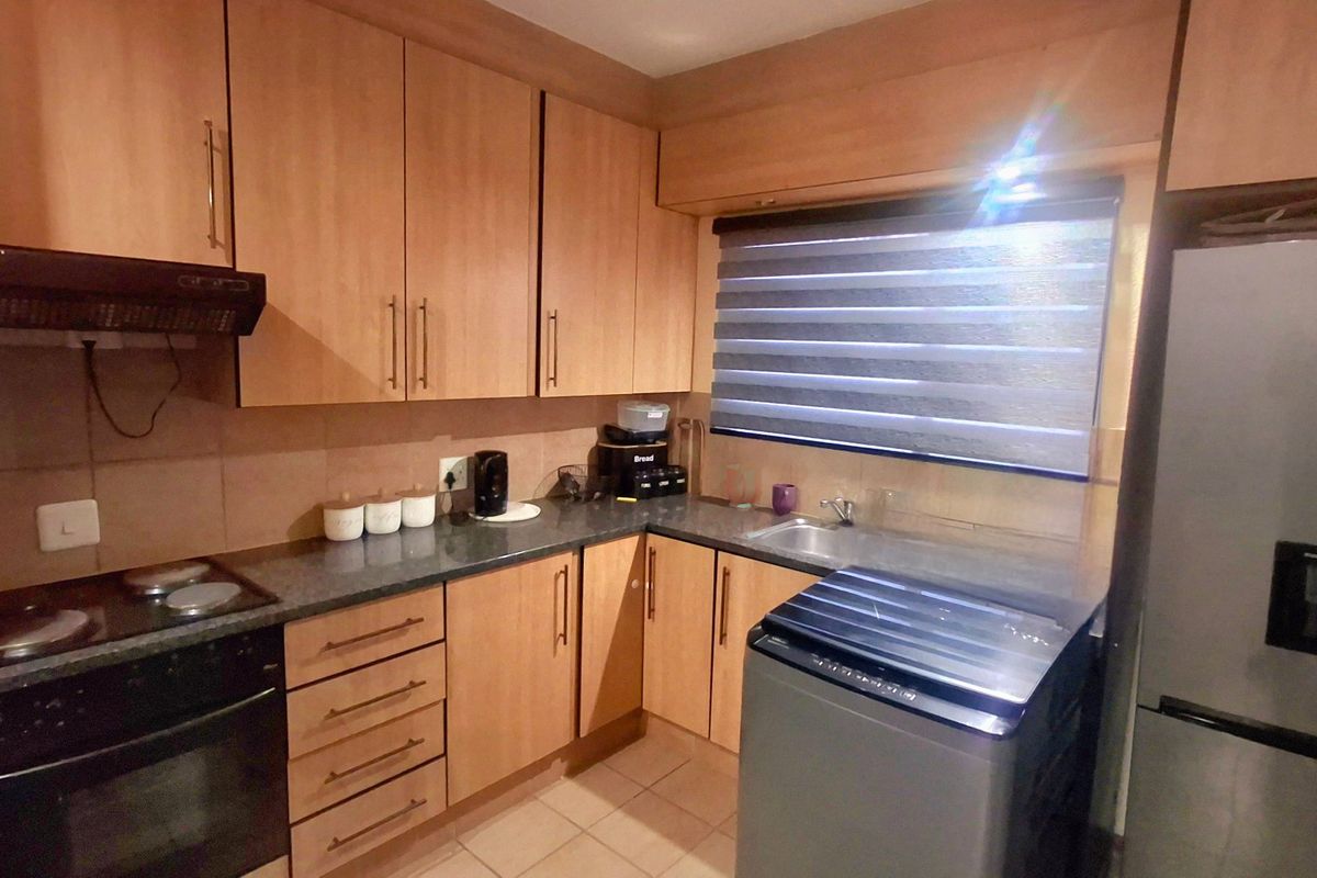 Functional kitchen featuring wood-look laminate cabinetry, granite countertops, built-in oven, electric hob, and a tiled backsplash.