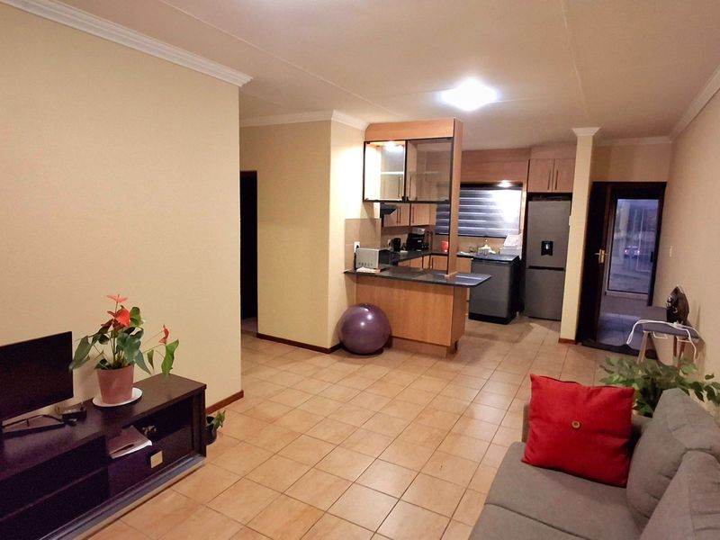 Open-plan living area featuring tiled flooring and a functional kitchen with built-in cabinetry and a breakfast bar.