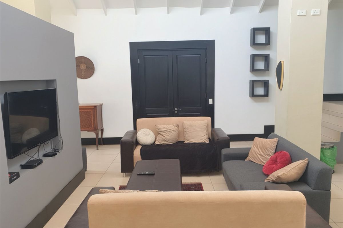 A spacious living room featuring a vaulted ceiling, tiled flooring, and a modern recessed media wall with double door access.
