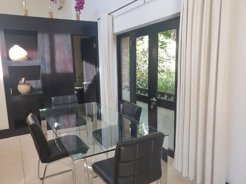 Dining area featuring a dark built-in shelving unit and glass french doors leading to an outdoor space with natural light.