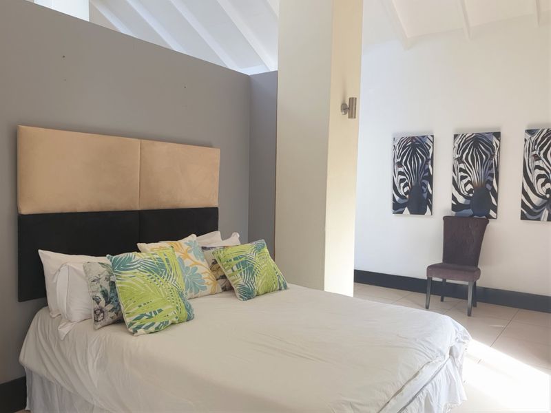 Spacious bedroom featuring high vaulted ceilings, neutral wall finishes, and tiled flooring, offering a bright and airy atmosphere.