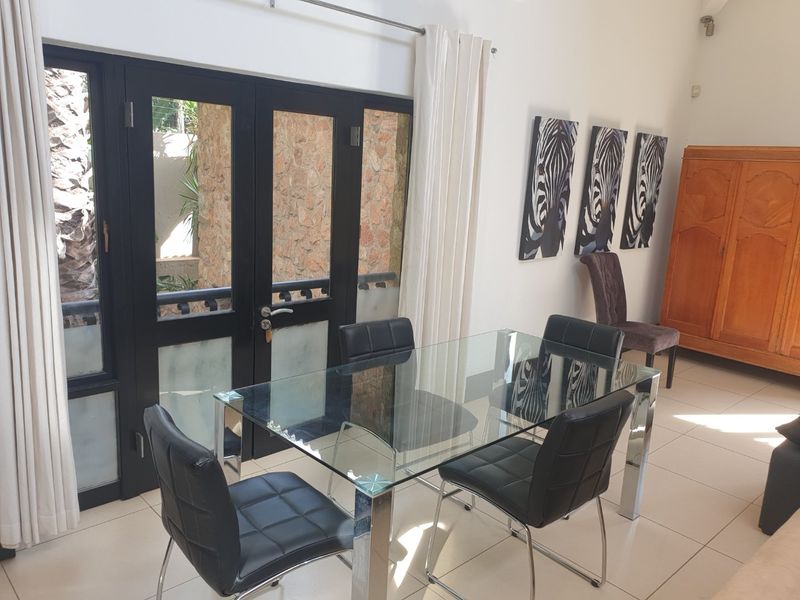 A bright dining area featuring tiled flooring and double glass panel doors that provide access to an outdoor space.