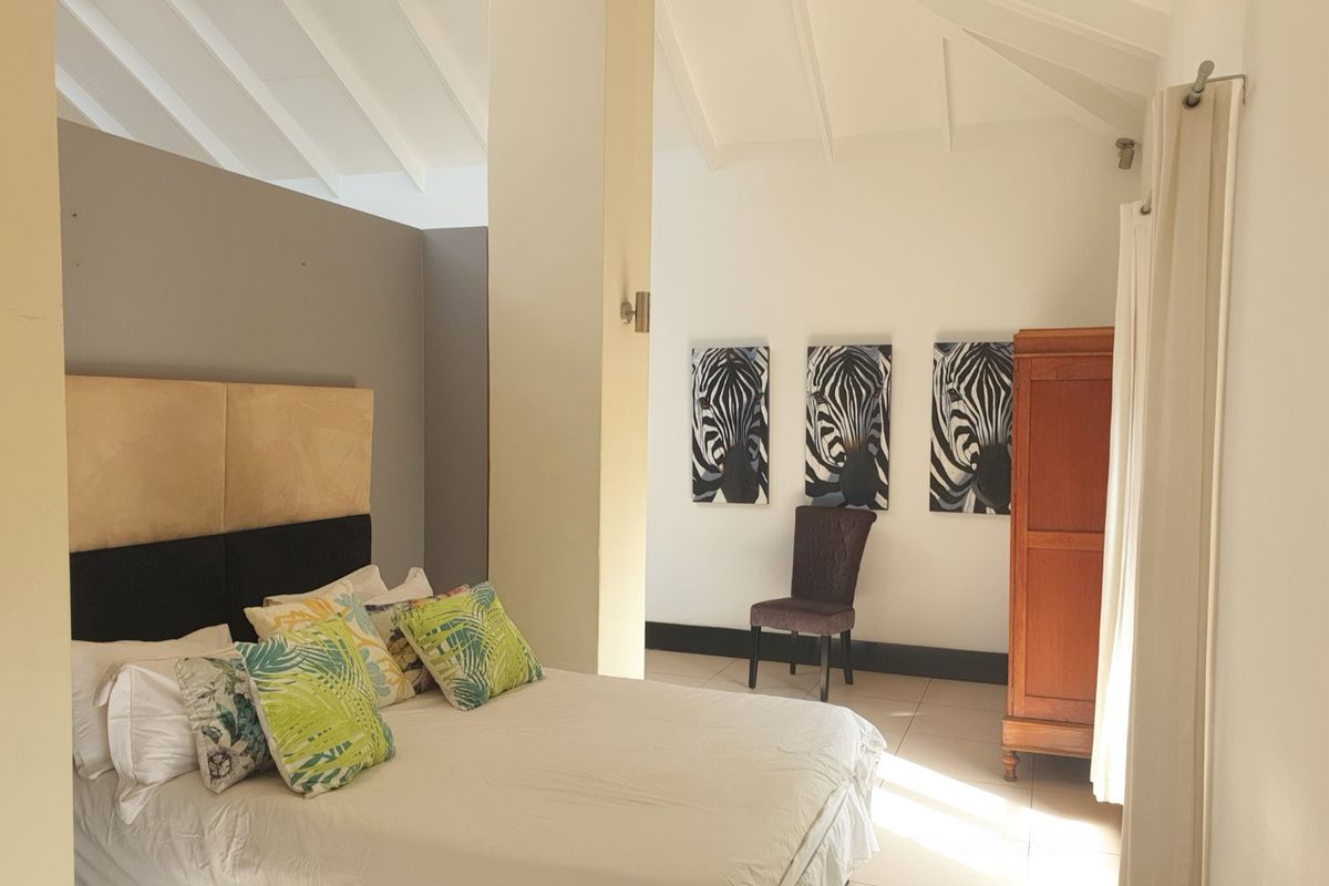 Spacious bedroom featuring a high vaulted ceiling, neutral tiled flooring, and a structural pillar, creating an open and airy atmosphere.