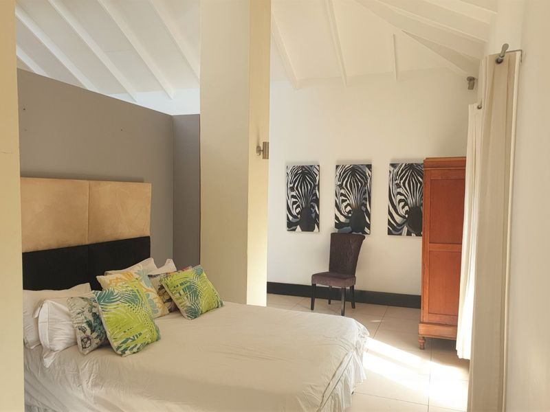 Spacious bedroom featuring a high vaulted ceiling, neutral tiled flooring, and a structural pillar, creating an open and airy atmosphere.
