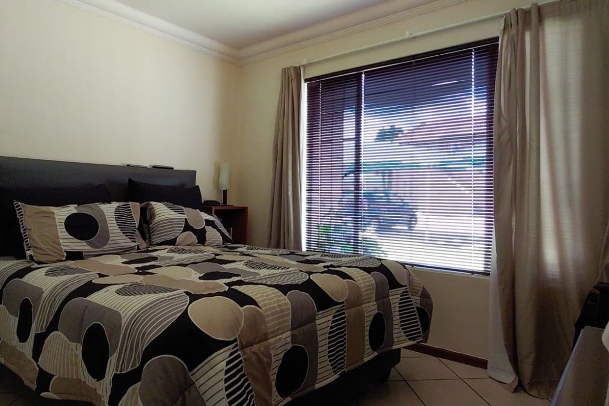 A functional bedroom featuring tiled flooring, window blinds, and curtain rails, offering a neutral base for potential interior updates.