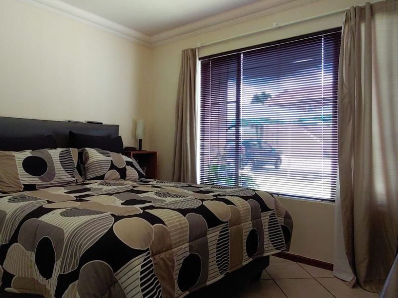 A functional bedroom featuring tiled flooring, window blinds, and curtain rails, offering a neutral base for potential interior updates.