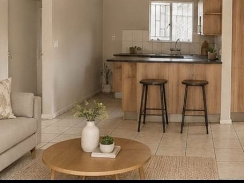 Open-plan living and dining area featuring tiled flooring and a functional kitchen with built-in cabinetry and a breakfast counter.