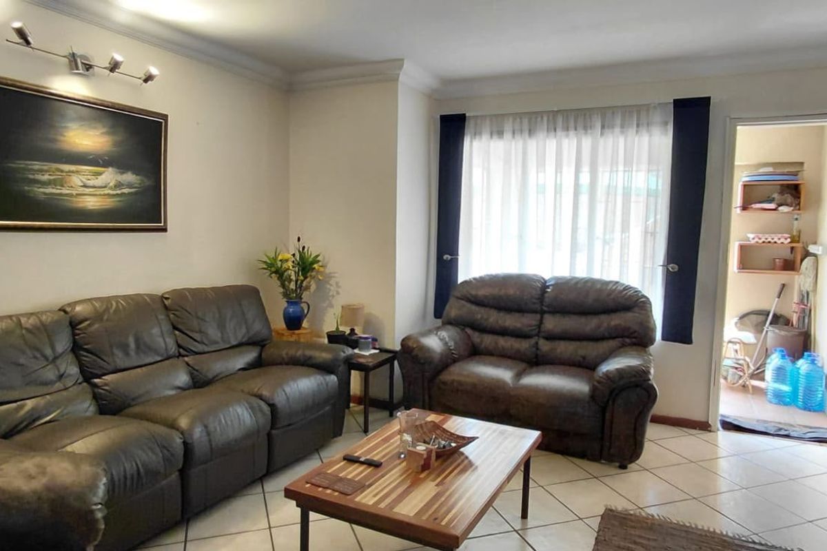 A comfortable living room featuring ceramic tile flooring, cove molding, and direct access to an adjacent utility or storage area.