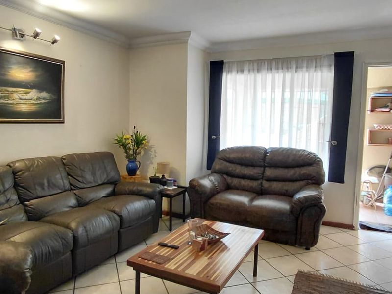 A comfortable living room featuring ceramic tile flooring, cove molding, and direct access to an adjacent utility or storage area.