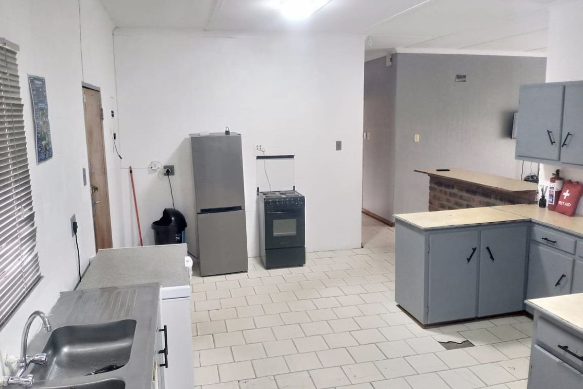 A functional kitchen featuring tiled flooring, built-in cabinetry, a brick breakfast bar, and a double basin sink, requiring cosmetic updates.