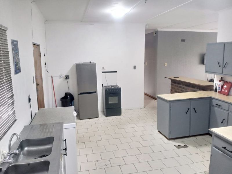 A functional kitchen featuring tiled flooring, built-in cabinetry, a brick breakfast bar, and a double basin sink, requiring cosmetic updates.