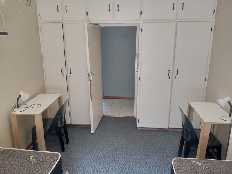 Bedroom featuring extensive built-in cupboard storage and carpeted flooring, offering a functional layout with potential for cosmetic updates.