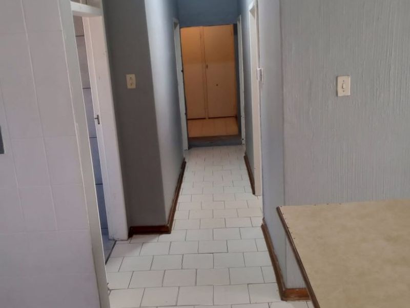 A functional hallway featuring tiled flooring and neutral wall finishes, providing access to multiple rooms within the property.