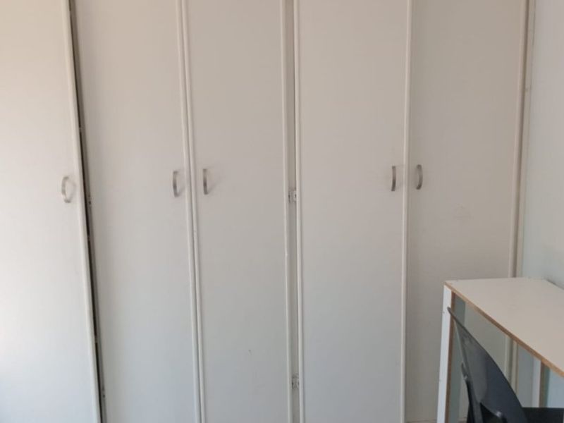 Bedroom featuring built-in cupboards with white finish and tiled flooring.