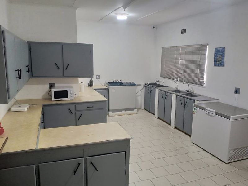 Functional laundry room featuring ample built-in cabinetry, double stainless steel sink, and tiled flooring, providing a practical space for household utility tasks.