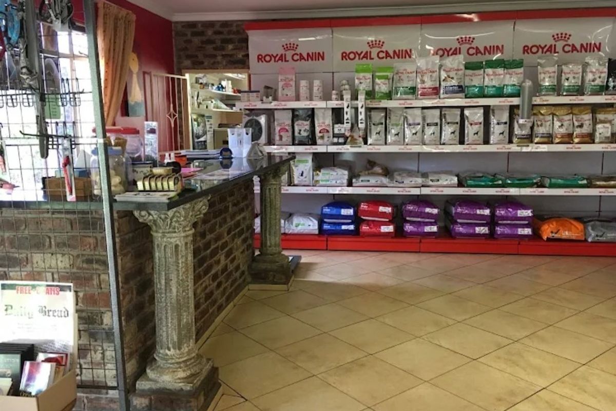 A commercial retail space featuring a brick service counter with decorative columns, tiled flooring, and extensive built-in shelving units.
