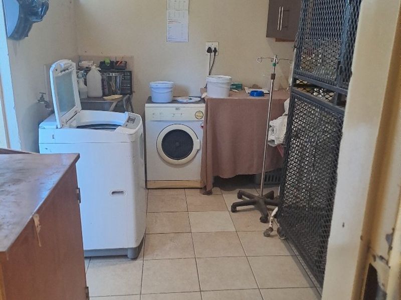 A functional laundry room featuring tiled flooring and built-in cabinetry, providing essential utility space for the property.