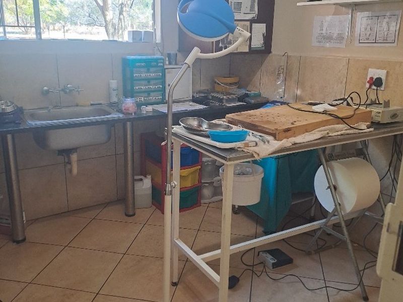 A functional utility or prep room featuring a stainless steel sink, tiled splashback, and ceramic flooring, suitable for various practical or workspace applications.
