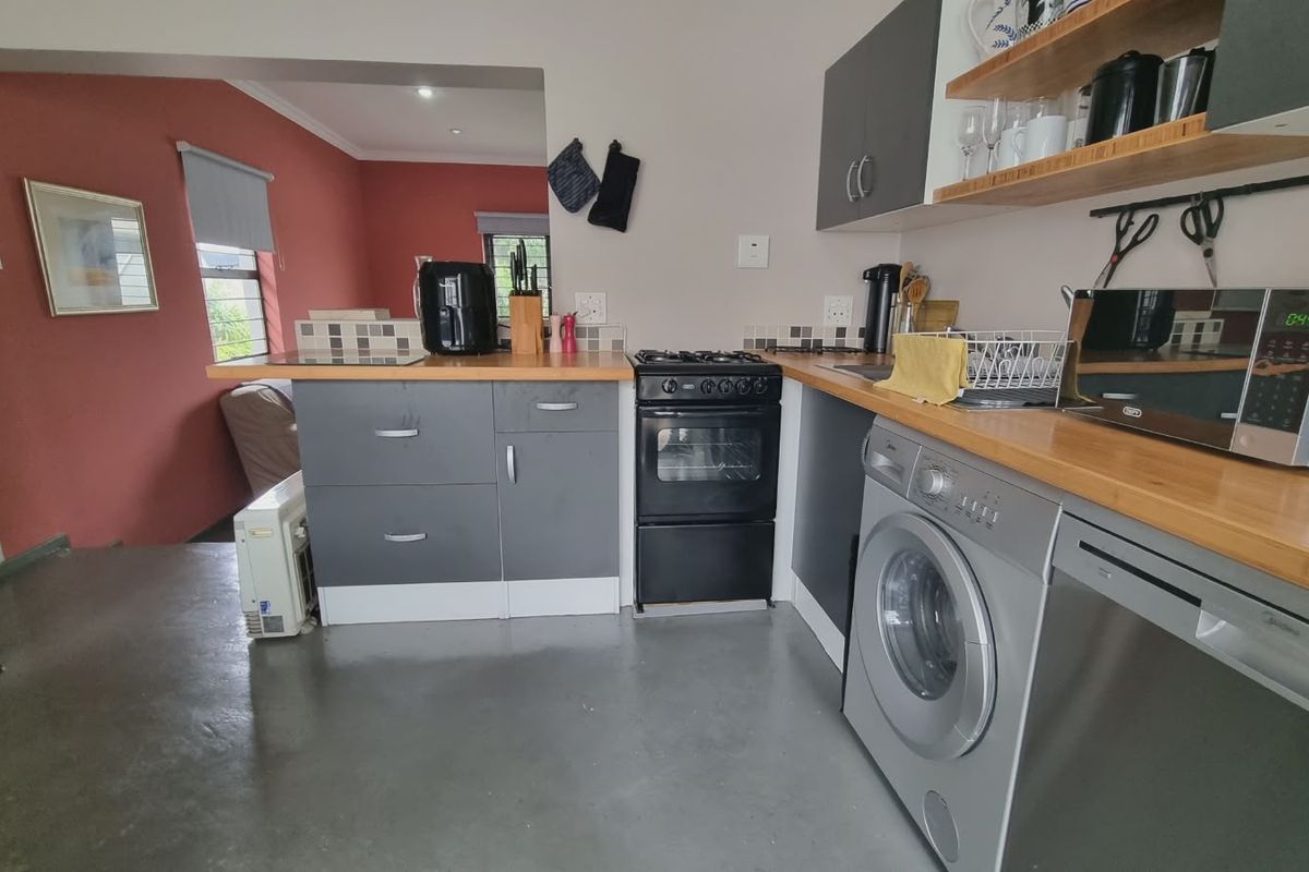 A functional kitchen featuring grey cabinetry, wooden countertops, a gas stove, and integrated laundry and dishwasher appliances.