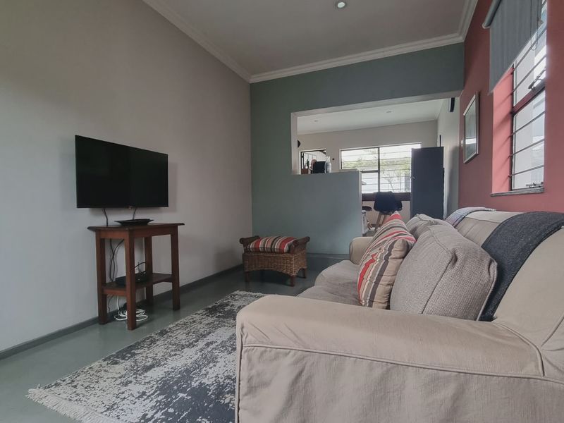 A comfortable living room featuring painted accent walls, security bars on the windows, and recessed ceiling lighting, providing a functional and cozy living space.