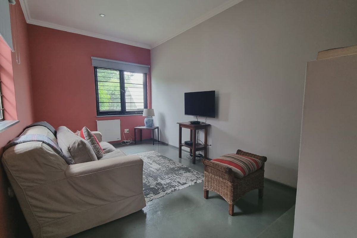 A living room featuring painted accent walls, aluminium window frames, and recessed downlighting, providing a functional and neutral living space.