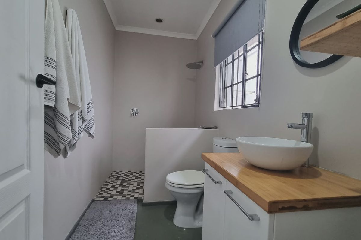 A modern bathroom featuring a vessel sink on a wooden vanity, a walk-in shower area, and a toilet, finished with neutral tones.