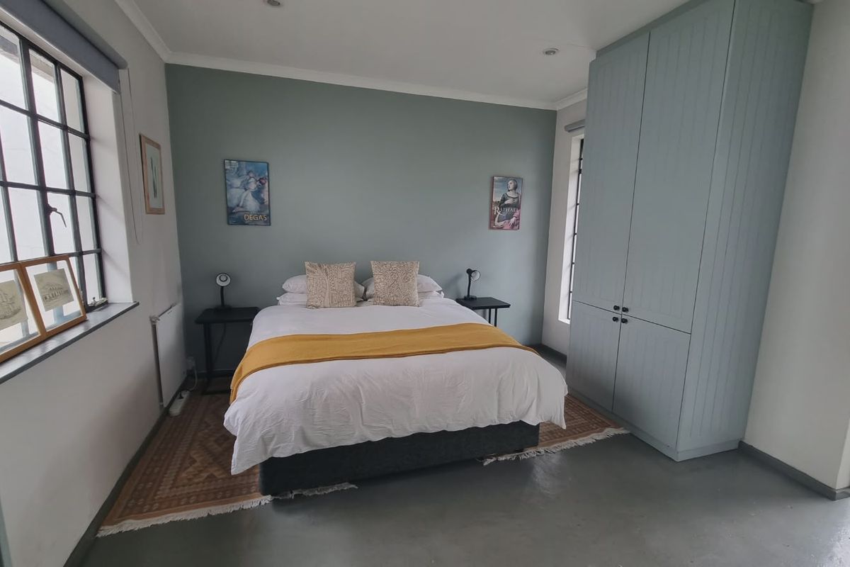 A well-maintained bedroom featuring polished concrete floors, built-in cabinetry, and large steel-framed windows providing natural light.