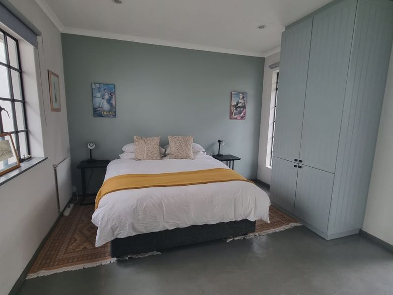 A well-maintained bedroom featuring polished concrete floors, built-in cabinetry, and large steel-framed windows providing natural light.