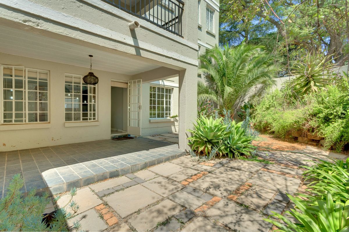 A ground floor apartment featuring a covered tiled patio, paved garden area, and direct access through french doors.