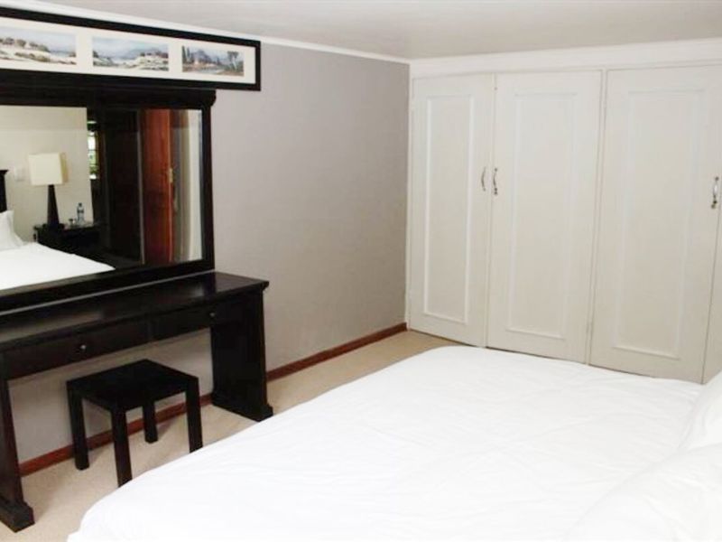 A bedroom featuring neutral wall tones, carpeted flooring, and ample built-in cupboard storage space.