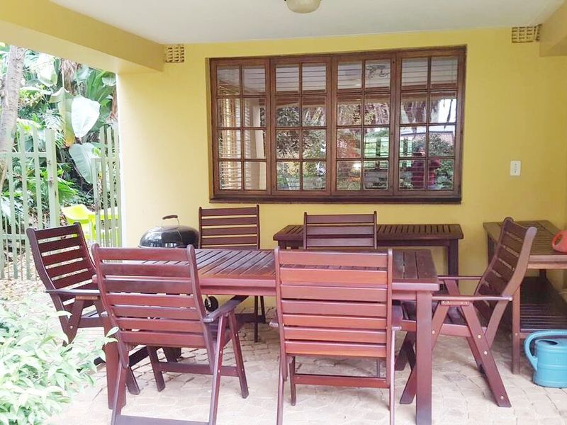 A covered outdoor patio area featuring paved flooring and timber-framed windows, providing a functional space for outdoor dining and relaxation.