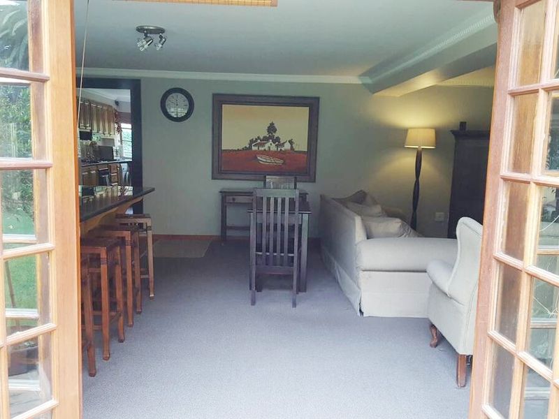 Open plan living and dining area featuring carpeted flooring and a breakfast bar, with direct access to the outdoors through wooden french doors.