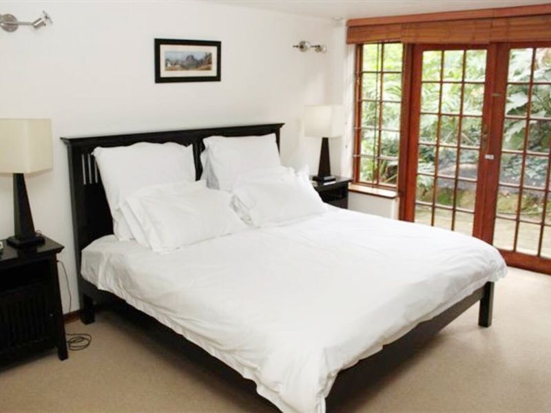 A comfortable bedroom featuring carpeted flooring and timber-framed glass doors that provide direct access to the garden area.
