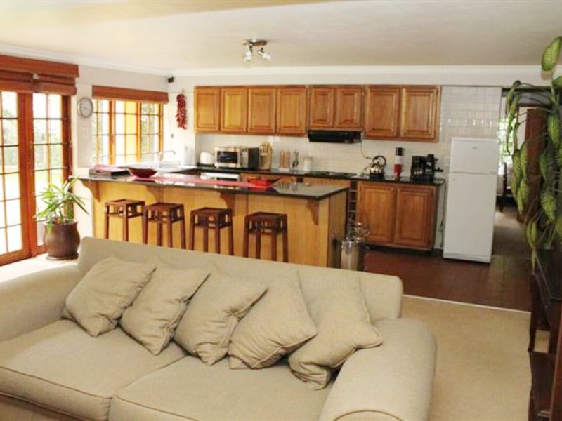 Open plan living and kitchen area featuring wooden cabinetry, granite countertops, and direct access to the outdoors through french doors.