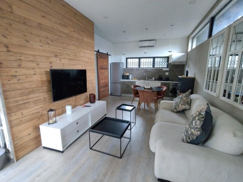 Open-plan living and kitchen area featuring a timber accent wall, modern cabinetry, and split-system air conditioning in a well-maintained townhouse setting.