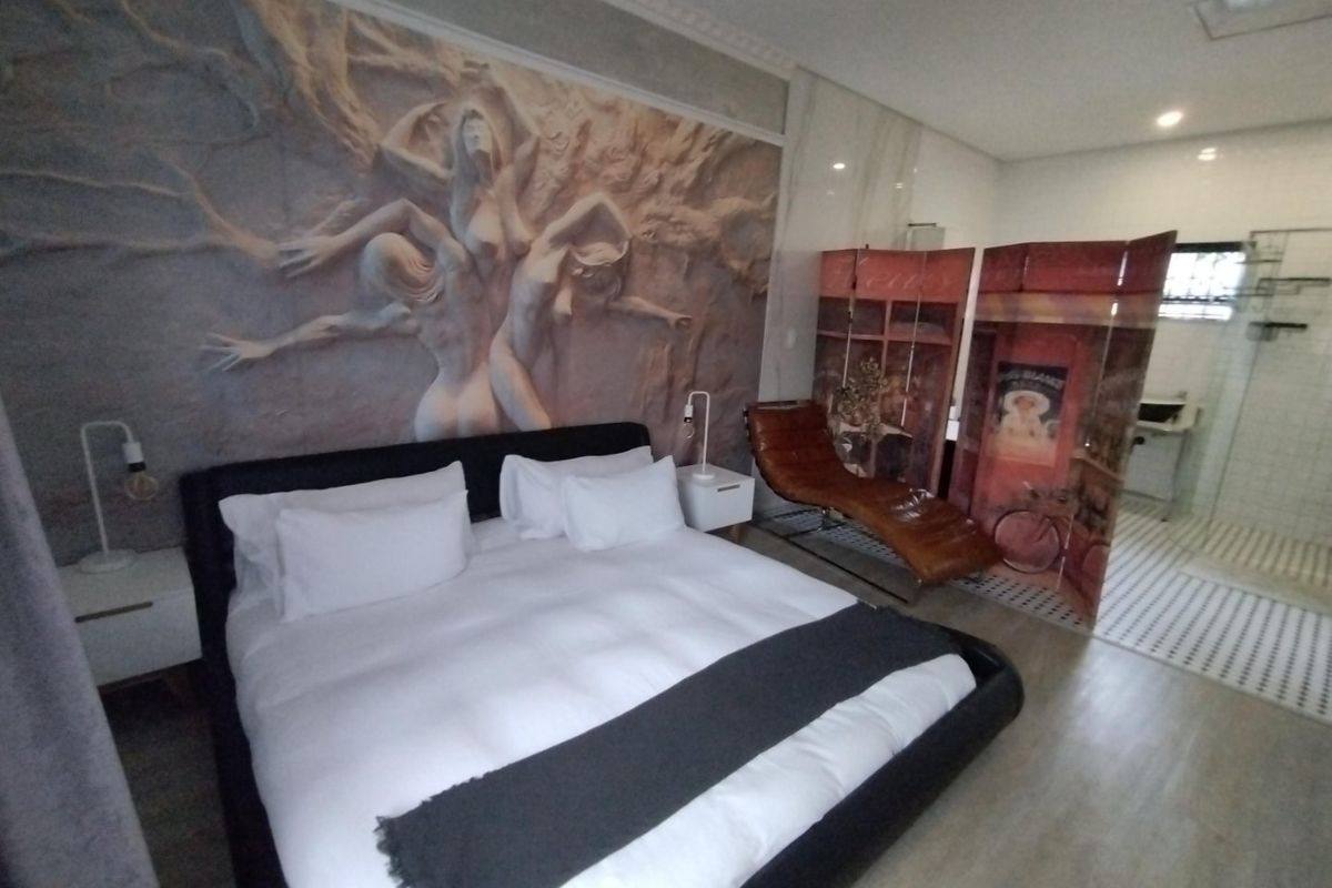 Spacious bedroom featuring a decorative relief wall mural, integrated en-suite bathroom with glass shower, and modern finishes.