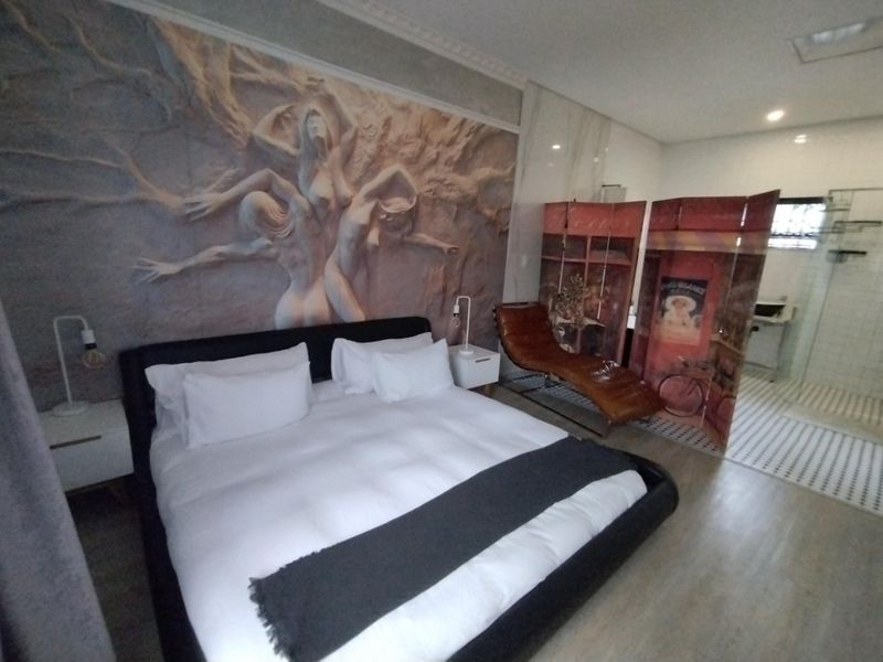 Spacious bedroom featuring a decorative relief wall mural, integrated en-suite bathroom with glass shower, and modern finishes.