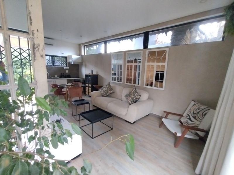 Open-plan living and kitchen area featuring laminate flooring, clerestory windows, and neutral wall finishes, offering a functional and connected living space.