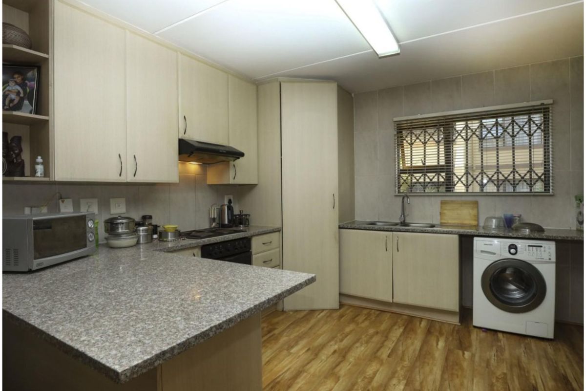 Functional kitchen featuring light wood-look cabinetry, granite countertops, integrated appliances, and durable vinyl flooring with a window providing natural light.