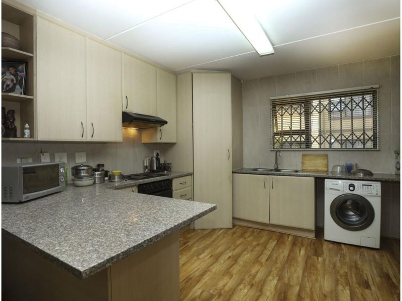 Functional kitchen featuring light wood-look cabinetry, granite countertops, integrated appliances, and durable vinyl flooring with a window providing natural light.