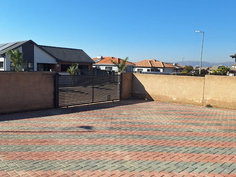 A paved front driveway area featuring a secure sliding gate and perimeter boundary wall in a residential neighborhood setting.