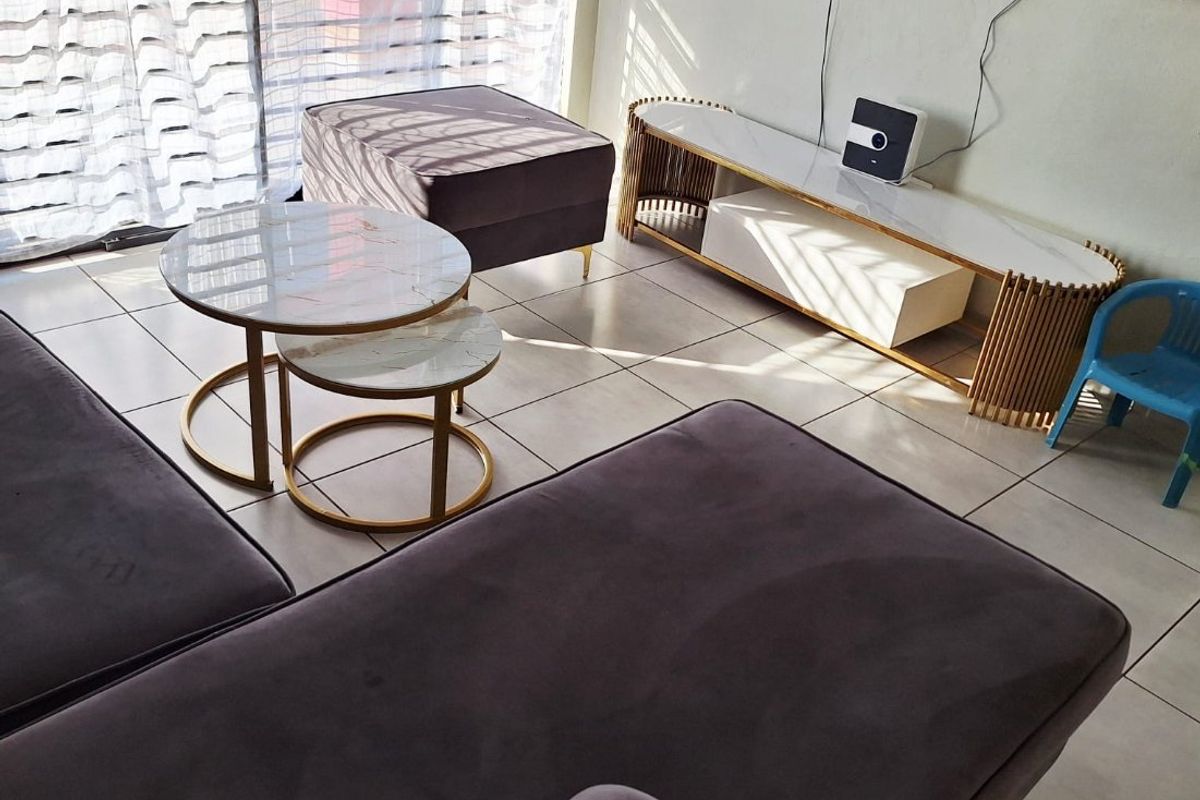 A living room area featuring light-colored floor tiles and a large sliding glass door providing natural light.